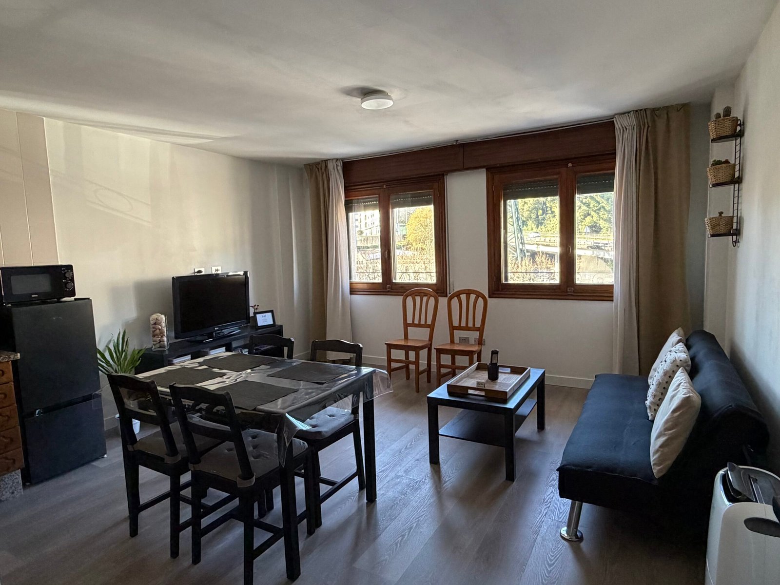 Salón comedor del Apartamento Sereno con sofá, mesa y ventanas al exterior